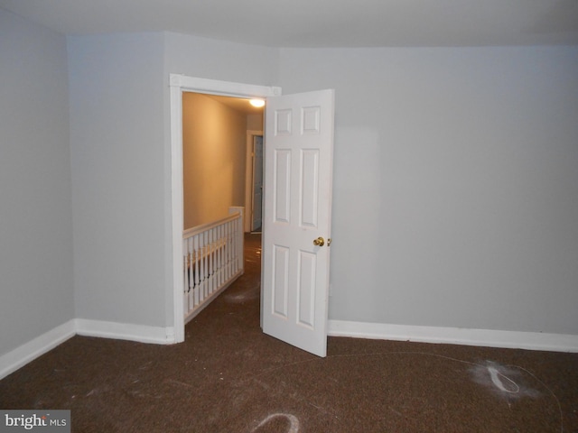 unfurnished room featuring dark colored carpet