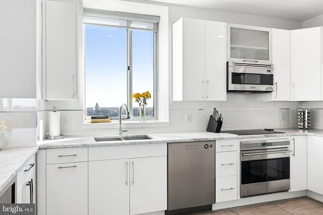 kitchen featuring decorative backsplash, appliances with stainless steel finishes, light stone counters, sink, and white cabinets