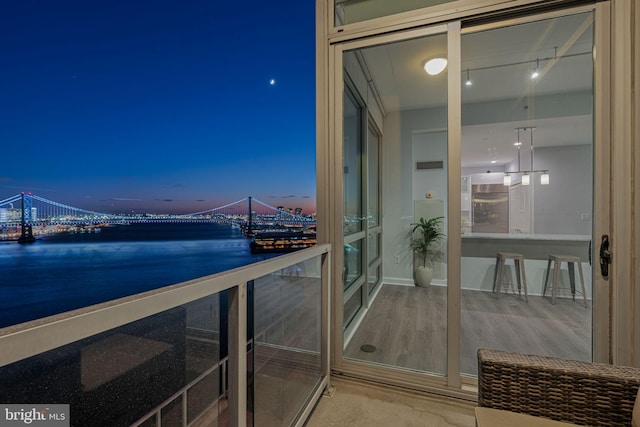 balcony at dusk featuring a water view