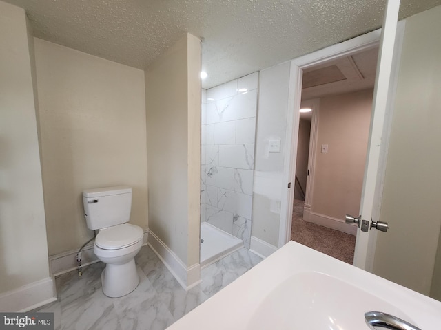 bathroom with a tile shower, a textured ceiling, and toilet