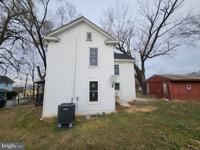 back of property featuring an outbuilding, central AC unit, and a lawn