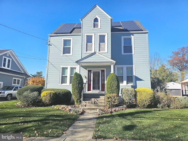 view of front of property with a front yard and solar panels