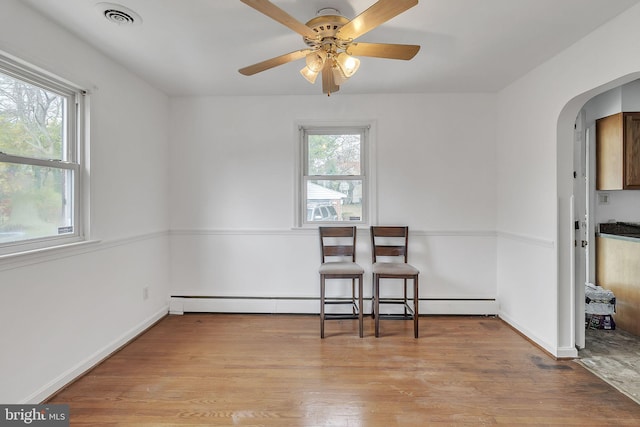 spare room featuring ceiling fan, baseboard heating, and light hardwood / wood-style flooring