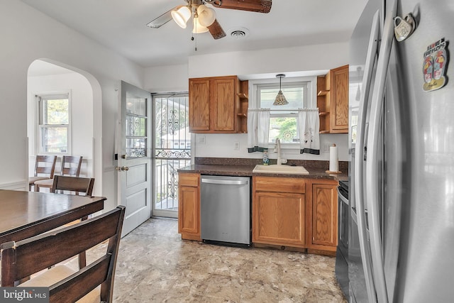 kitchen with a wealth of natural light, sink, hanging light fixtures, and appliances with stainless steel finishes