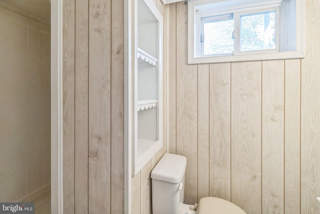 bathroom with wood walls and toilet