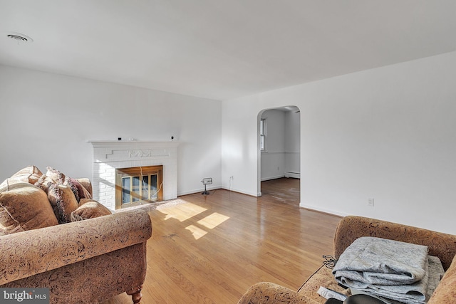 living room featuring a fireplace, a baseboard heating unit, and hardwood / wood-style flooring