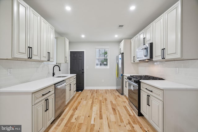 kitchen with white cabinets, sink, light wood-type flooring, and stainless steel appliances