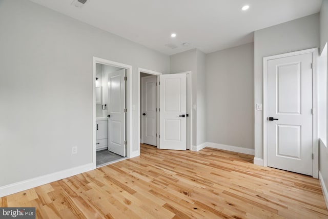 unfurnished bedroom with light wood-type flooring and ensuite bathroom