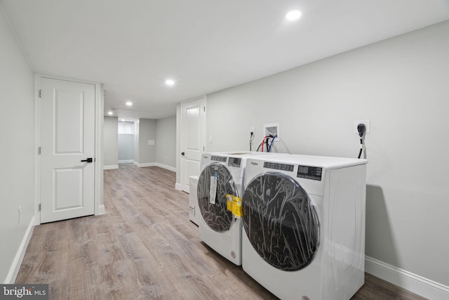 clothes washing area featuring washing machine and dryer and light hardwood / wood-style floors