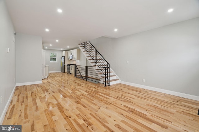 3013 Wharton St, Philadelphia, PA 19146 - unfurnished living room with light wood finished floors, recessed lighting, baseboards, and stairs