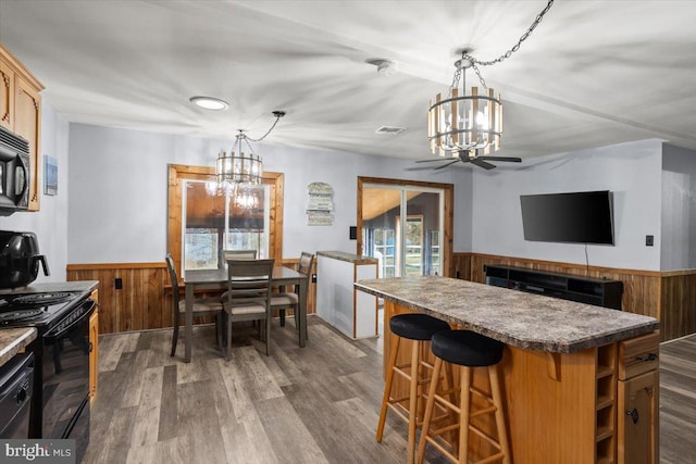 kitchen featuring dark hardwood / wood-style flooring, a center island, black appliances, and decorative light fixtures