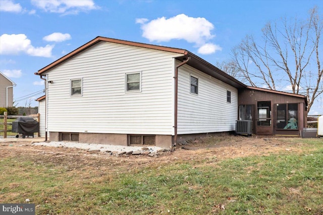 view of side of property with a sunroom, central air condition unit, and a lawn