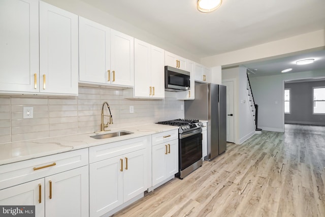 kitchen featuring white cabinets, appliances with stainless steel finishes, light wood-type flooring, and sink