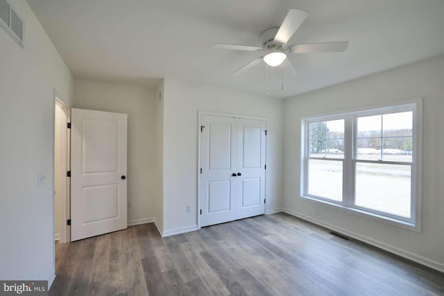 unfurnished bedroom with hardwood / wood-style floors, ceiling fan, and a closet