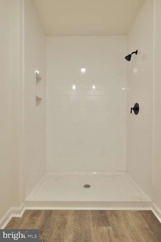 bathroom featuring hardwood / wood-style flooring and a tile shower