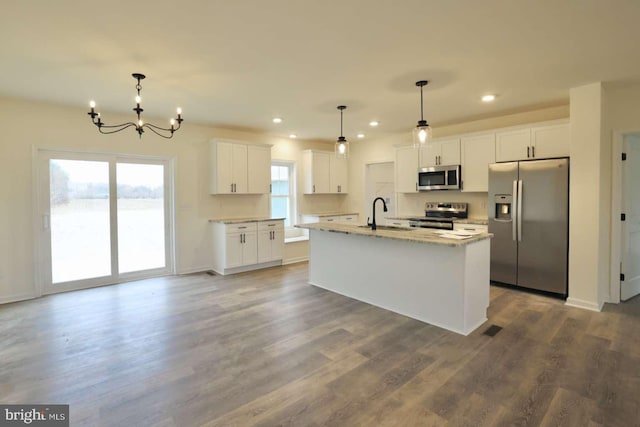 kitchen featuring hardwood / wood-style flooring, an island with sink, decorative light fixtures, white cabinetry, and stainless steel appliances