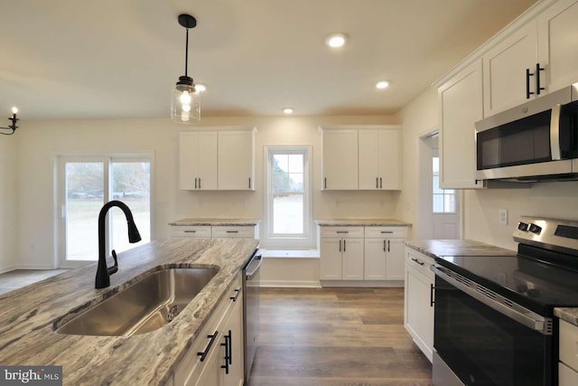 kitchen featuring light stone countertops, sink, stainless steel appliances, white cabinets, and hardwood / wood-style flooring