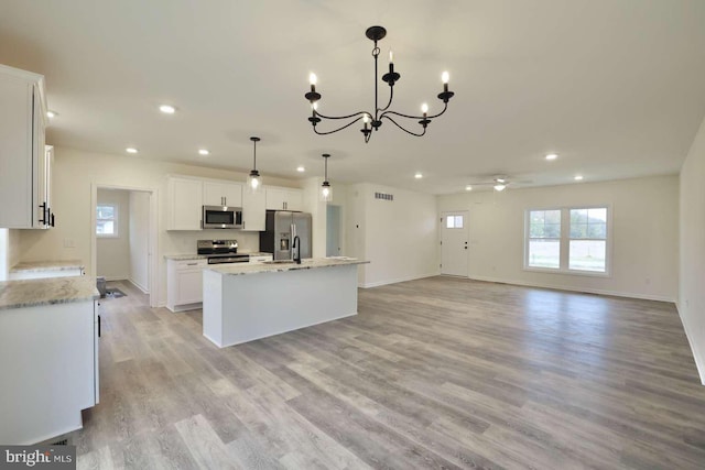 kitchen featuring pendant lighting, a kitchen island with sink, light hardwood / wood-style flooring, white cabinetry, and stainless steel appliances