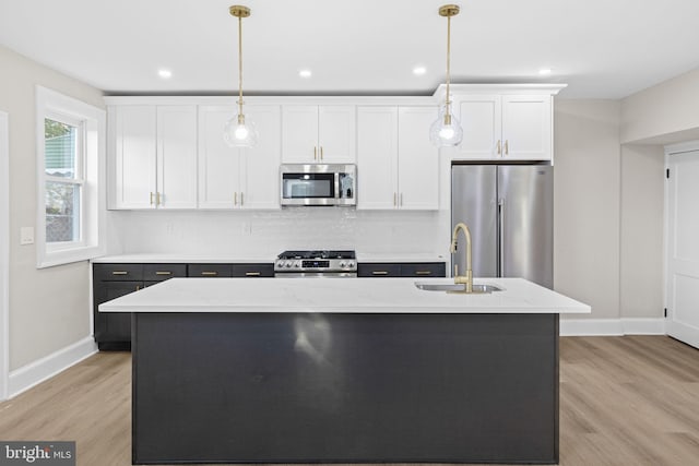 kitchen with sink, light stone counters, a center island with sink, white cabinets, and appliances with stainless steel finishes