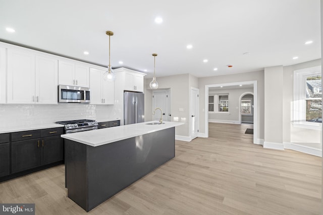 kitchen featuring pendant lighting, a center island with sink, sink, light hardwood / wood-style flooring, and stainless steel appliances