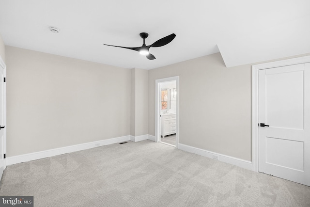 unfurnished bedroom with ceiling fan, light carpet, and connected bathroom