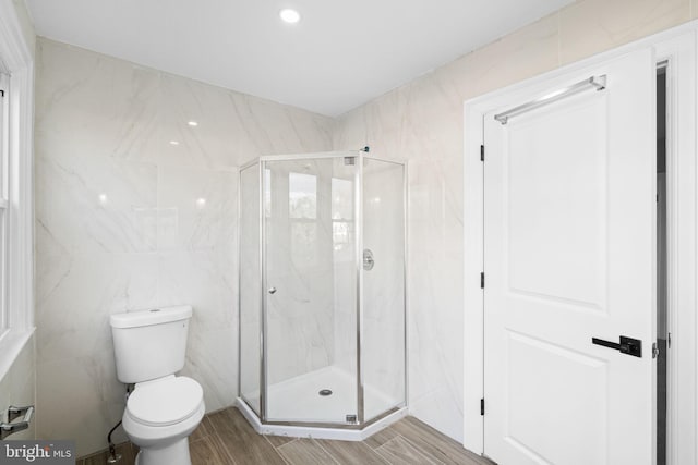 bathroom featuring wood-type flooring, a shower with door, and tile walls