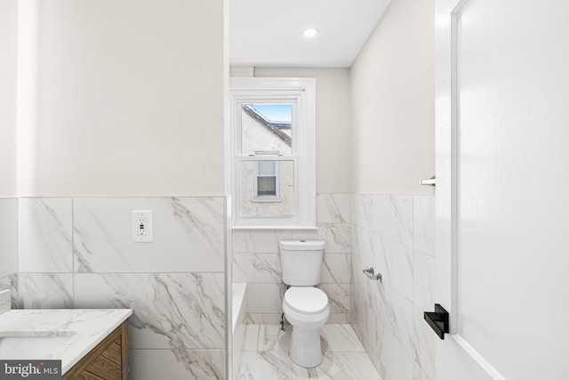 bathroom featuring vanity, tile walls, and toilet