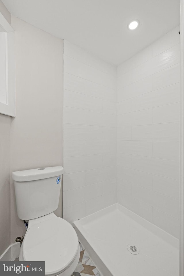 bathroom with a tile shower and toilet