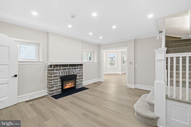 living room featuring ornamental molding, a fireplace, and light hardwood / wood-style flooring