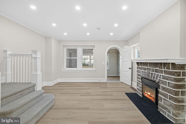 living room with crown molding, a fireplace, and light wood-type flooring