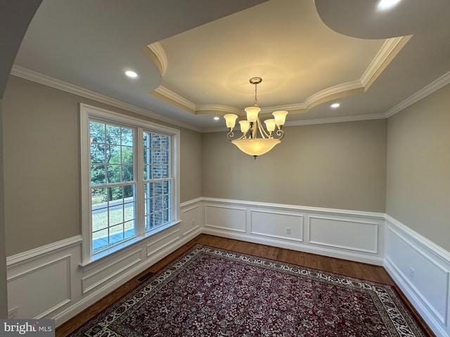 spare room with hardwood / wood-style floors, crown molding, a tray ceiling, and an inviting chandelier