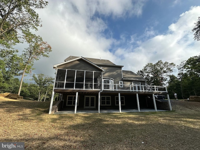 back of property with a sunroom, a deck, a yard, and a patio