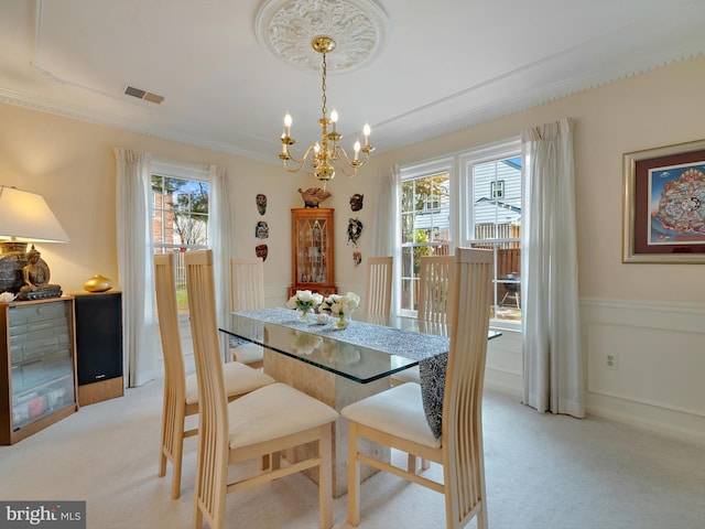 dining space with a chandelier, light colored carpet, and ornamental molding