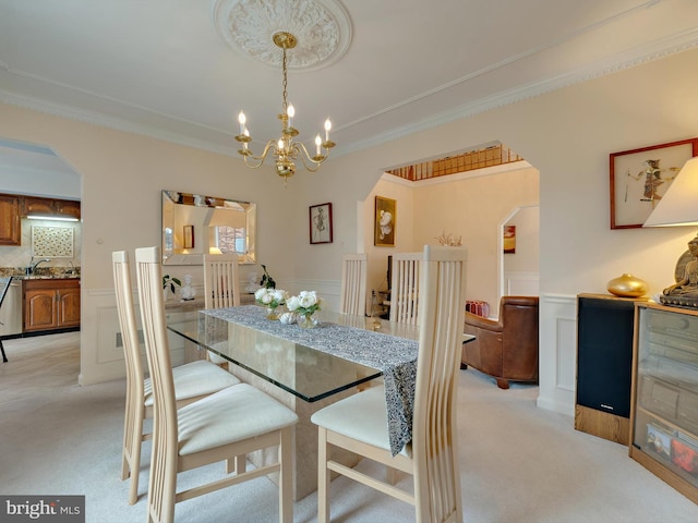 carpeted dining area featuring crown molding, sink, and a chandelier