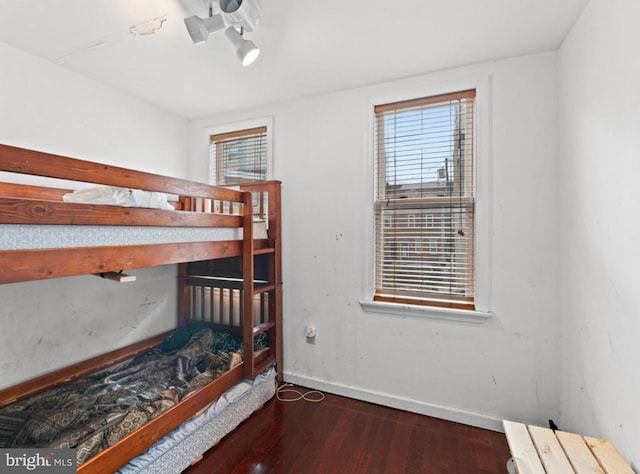 bedroom with multiple windows and dark wood-type flooring