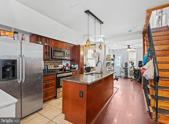 kitchen with pendant lighting, sink, ceiling fan, an island with sink, and stainless steel appliances