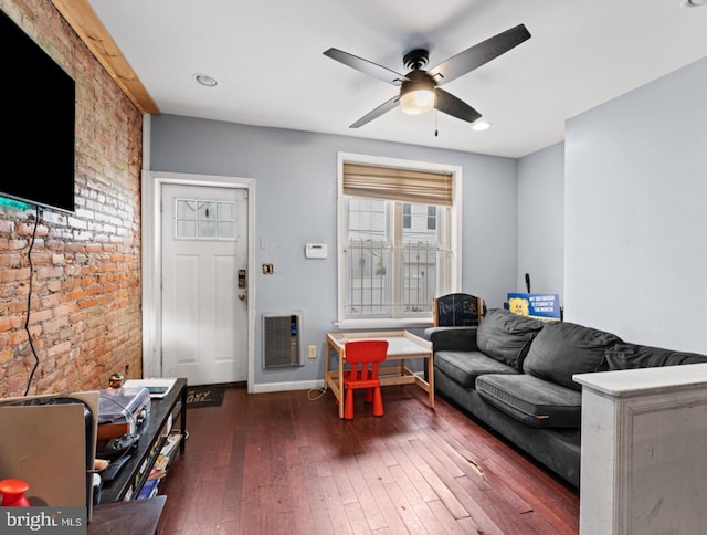 living room featuring heating unit, ceiling fan, dark hardwood / wood-style flooring, and brick wall