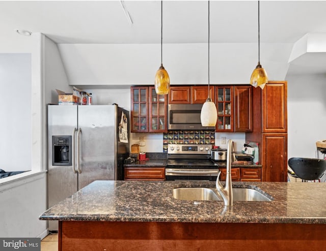 kitchen with pendant lighting, sink, stainless steel appliances, and dark stone countertops