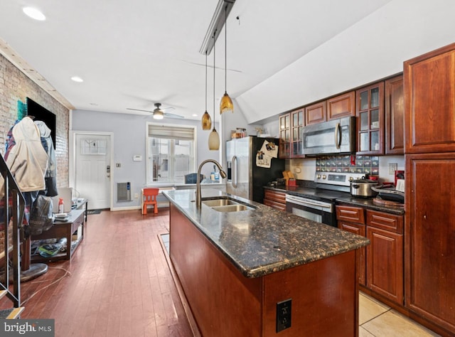 kitchen featuring sink, an island with sink, decorative light fixtures, light hardwood / wood-style floors, and stainless steel appliances