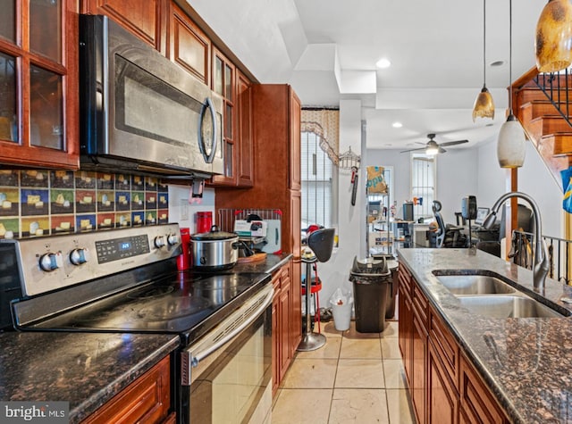 kitchen featuring ceiling fan, sink, hanging light fixtures, stainless steel appliances, and dark stone counters