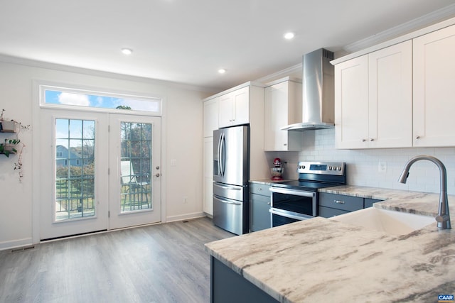 kitchen with appliances with stainless steel finishes, white cabinetry, and wall chimney exhaust hood