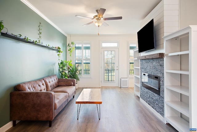 living room featuring a fireplace, hardwood / wood-style flooring, ceiling fan, and crown molding