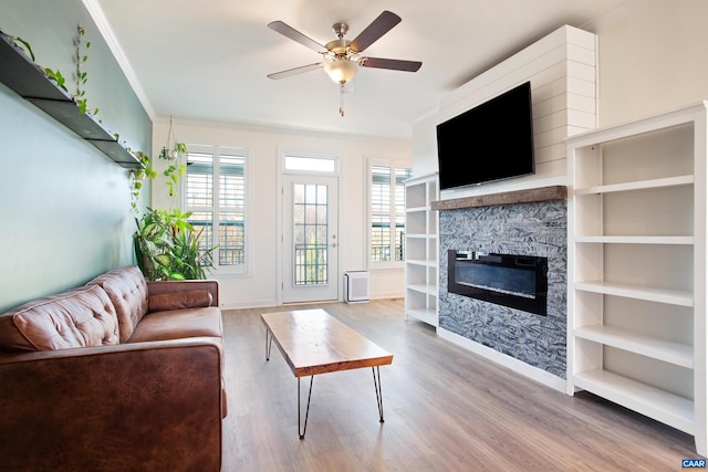 unfurnished living room featuring ceiling fan, light hardwood / wood-style floors, crown molding, and a fireplace