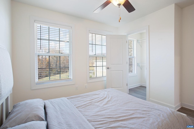 bedroom with a closet, dark hardwood / wood-style floors, multiple windows, and ceiling fan