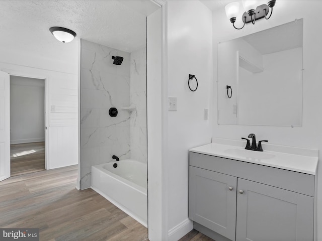 bathroom with vanity, wood-type flooring, a textured ceiling, and tiled shower / bath