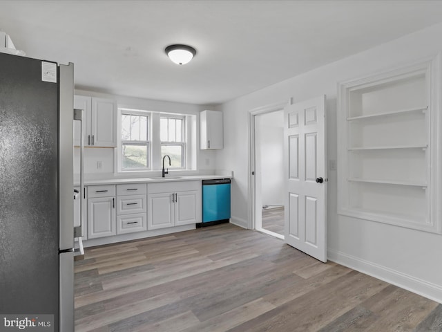 kitchen with appliances with stainless steel finishes, light wood-type flooring, and white cabinetry