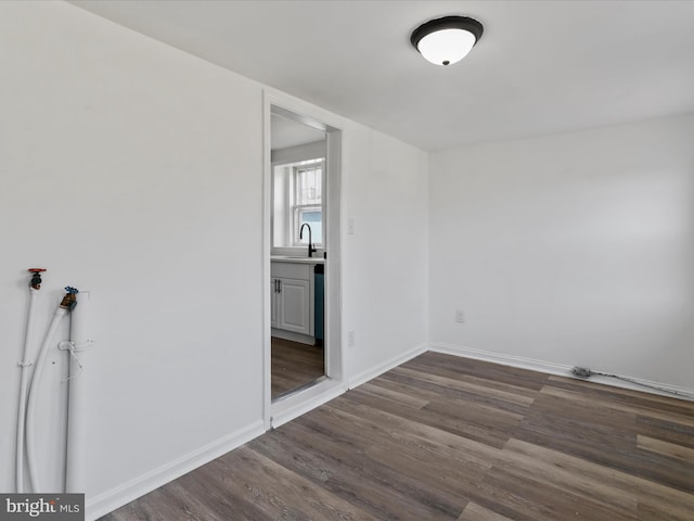 spare room with sink and dark wood-type flooring