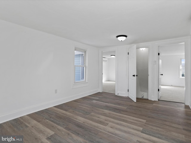 unfurnished bedroom with a wall unit AC and dark wood-type flooring