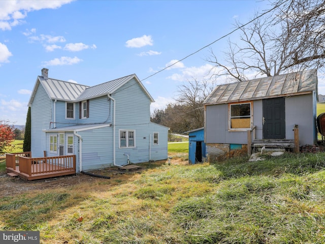 back of house with a yard, a wooden deck, and an outbuilding