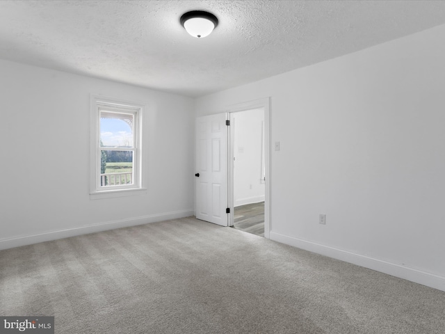 empty room with carpet floors and a textured ceiling